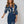 Stijlvolle vrouw in blauwe bloemenjurk met lange mouwen, elegante uitstraling, modetrend, casual chique outfit, modeaccessoires, moderne look.