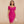 Vrouw in roze off-shoulder bodycon jurk, elegante knielengte, geschikt voor zomerfeest of club, met gouden oorbellen en witte clutch.