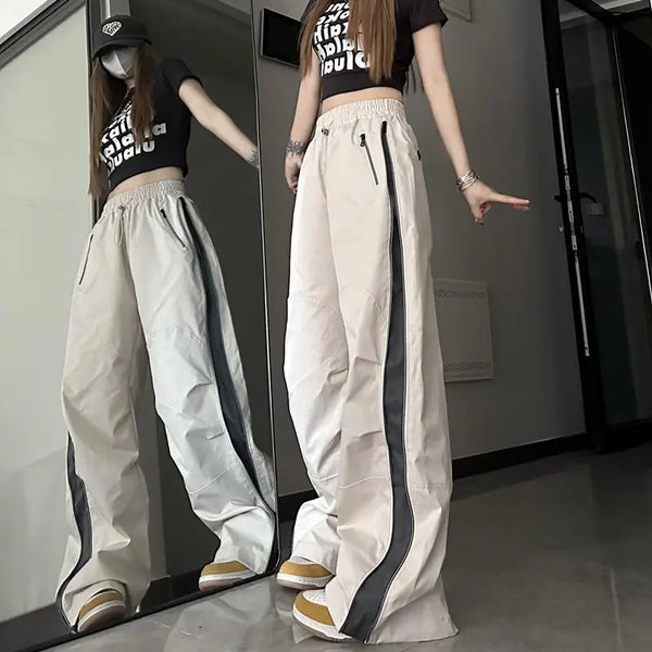 Vrouw in beige wijde broek met zwarte strepen, crop top en pet poseert voor spiegel. Trendy streetwear mode, casual outfit, moderne stijl.