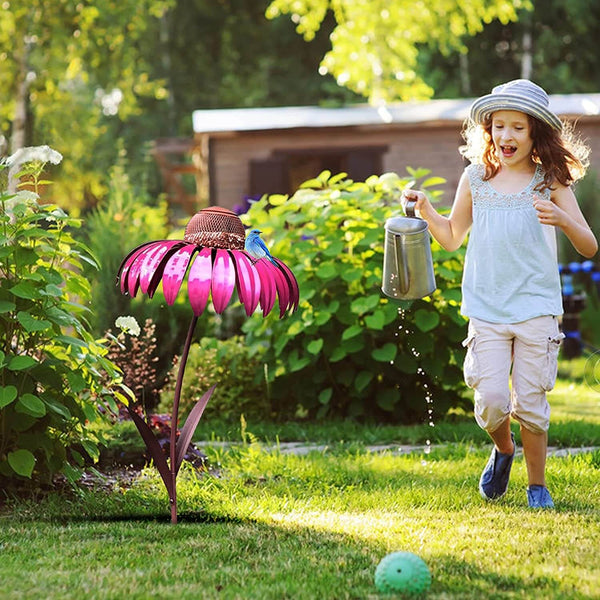 Meisje met gieter naast roze bloemvormige vogelvoeder in tuin, zonnige dag, groene achtergrond. Perfect voor tuinliefhebbers en vogelspotters.