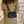 Vrouw met beige jas draagt zwarte leren schoudertas met kettingriem. Stijlvolle handtas, modieuze accessoire, trendy damesmode.