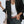 Vrouw in zwarte blazer met witte top en groene broek, draagt beige tas. Stijlvolle zakelijke outfit, mode voor dames, casual chic look.