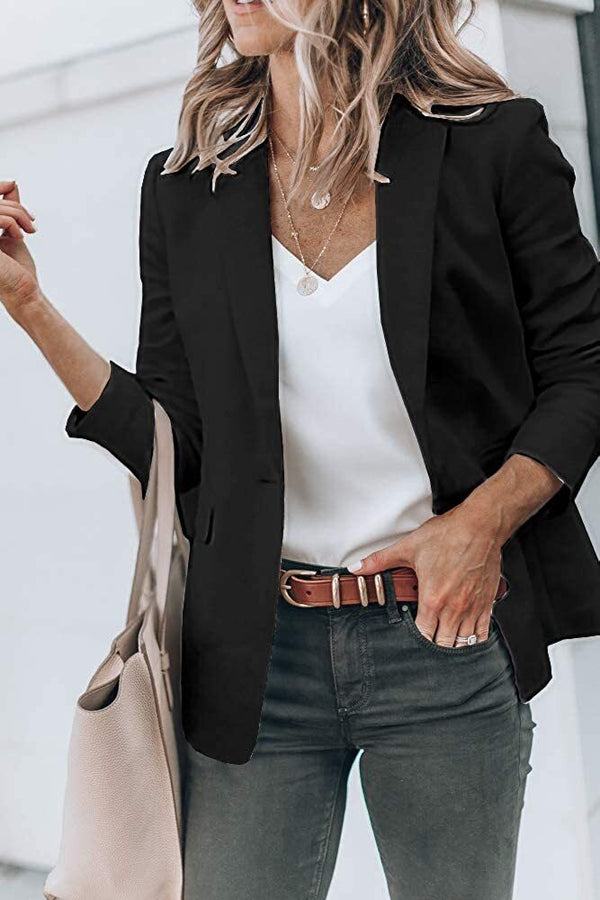 Vrouw in zwarte blazer met witte top en groene broek, draagt beige tas. Stijlvolle zakelijke outfit, mode voor dames, casual chic look.