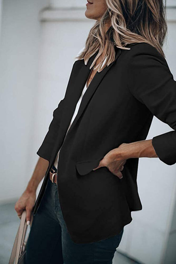 Vrouw in zwarte blazer met opgerolde mouwen, witte blouse en jeans. Stijlvolle zakelijke outfit, mode voor kantoor en casual gelegenheden.