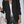Vrouw in zwarte blazer met witte blouse en spijkerbroek, draagt een beige handtas. Stijlvolle zakelijke outfit voor damesmode.
