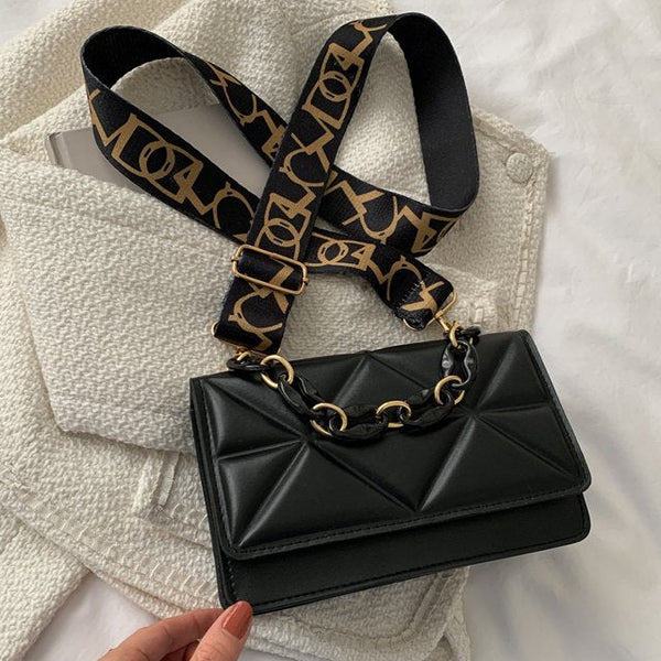 Zwarte leren handtas met gewatteerd patroon en gouden kettingriem, op witte achtergrond. Luxe damesaccessoire, modieuze schoudertas.
