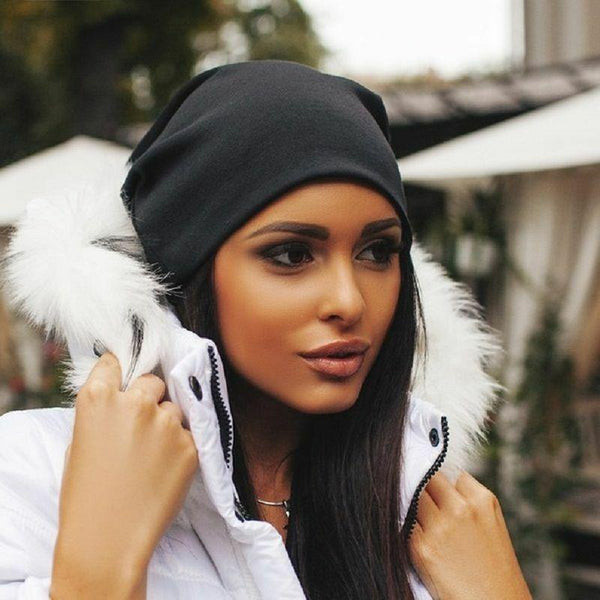 Vrouw met zwarte muts en witte winterjas met bontkraag, buiten in herfstomgeving. Modieuze winterkleding, trendy accessoires, herfststijl.