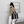 Vrouw met zwarte hoed en beige vest draagt een gestreepte zwarte tas en houdt een koffiebeker vast. Stijlvolle mode, casual outfit, trendy accessoires.