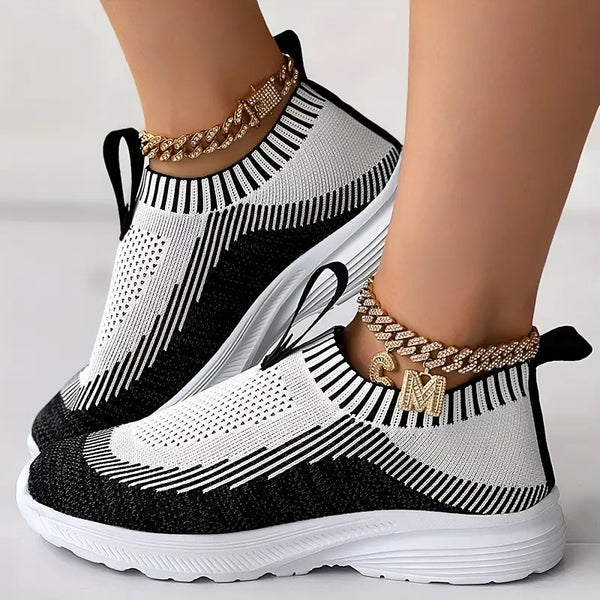 Zwart-witte sneakers met gebreid patroon en dikke zool, versierd met gouden enkelbandjes. Trendy damesmode, comfortabele sportschoenen.
