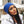 Vrouw met blauwe muts en witte winterjas met bontkraag, buiten in stedelijke omgeving. Wintermode, stijlvolle accessoires, koude seizoenen.