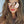 Vrouw met lange golvende haren draagt roze aviator zonnebril en feloranje lippenstift. Modieuze dameszonnebril, trendy accessoire.