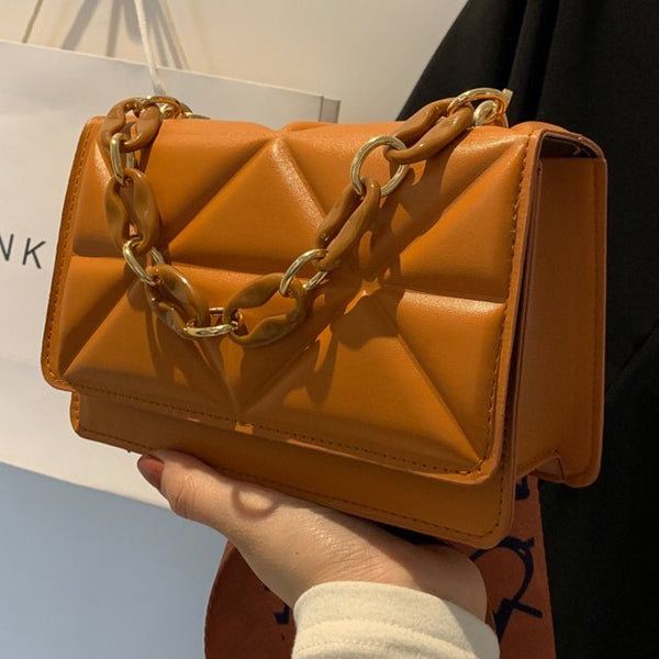 Oranje leren handtas met gouden ketting, geometrisch ontwerp. Trendy damesaccessoire, perfect voor modieuze outfits en dagelijks gebruik.