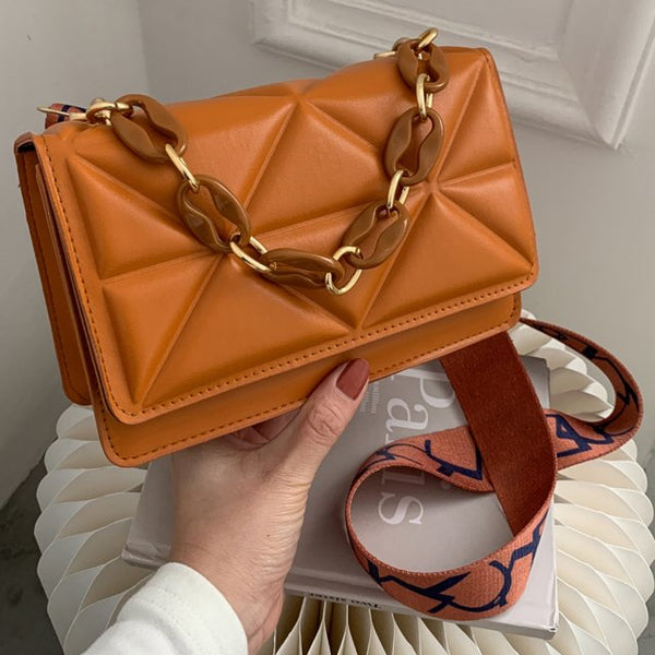 Oranje leren handtas met geometrisch patroon, goudkleurige ketting en verstelbare schouderriem. Trendy damesaccessoire voor dagelijks gebruik.