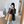 Vrouw met zwarte hoed en grijze blazer maakt selfie in moderne kamer, draagt grote gestreepte bruine tas. Mode, accessoires, binnenruimte.