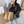 Vrouw met bruine gestreepte handtas, rode handvatten, grijze blazer en jeans in moderne winkelomgeving. Stijlvolle modeaccessoires, casual chic.