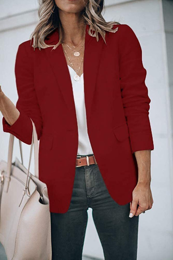 Vrouw in bordeauxrode blazer, witte blouse en jeans, met beige handtas. Stijlvolle zakelijke outfit, mode voor dames, herfstkleding.