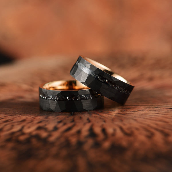 Twee zwarte tungsten trouwringen met diamantaccenten op houten achtergrond, moderne en duurzame trouwringen voor koppels, luxe sieraden.
