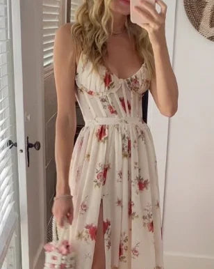 Vrouw in bloemenjurk met roze en rode bloemenpatroon, poseert voor spiegel. Zomerse outfit, elegante stijl, perfect voor casual en feestelijke gelegenheden.