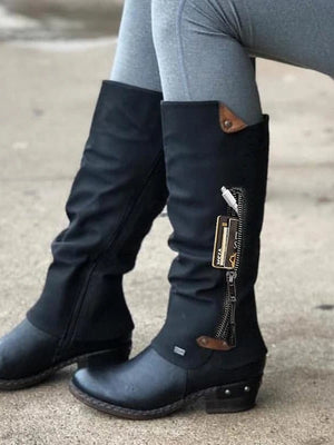 Zwarte hoge laarzen met opbergvak, ritssluiting en bruine accenten, gedragen door persoon in grijze legging. Stijlvolle en praktische dameslaarzen.