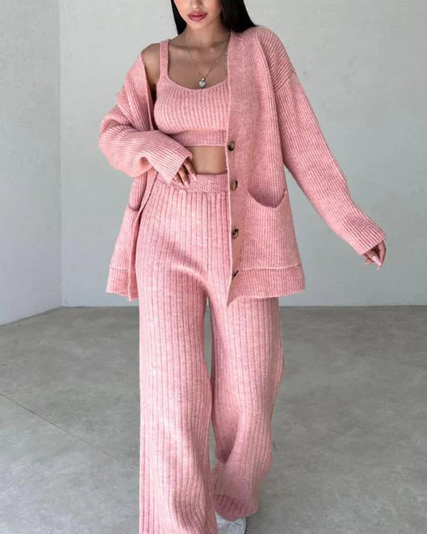 Vrouw in roze gebreid loungepak met vest, top en broek. Comfortabele damesmode, trendy huisstijl, perfect voor casual en ontspannen dagen.