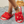 Rode pluche slippers met gouden accenten op een grijze vloermat, gedragen door een persoon met een gouden enkelband. Luxe damesmode, comfortabele huisslippers.