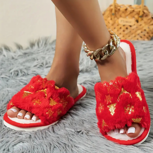 Rode pluche slippers met gouden accenten op een grijze vloermat, gedragen door een persoon met een gouden enkelband. Luxe damesmode, comfortabele huisslippers.