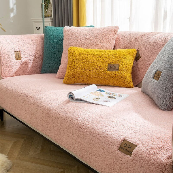 Roze bank met ultra zachte bankhoes, kleurrijke kussens en open tijdschrift op houten vloer. Perfect voor moderne woonkamerinrichting.