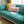 Turquoise bank met ultra zachte hoes, kleurrijke kussens en open tijdschrift op houten vloer. Perfecte woonkamerinrichting, moderne stijl.