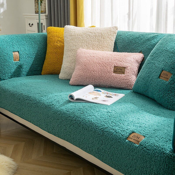 Turquoise bank met ultra zachte hoes, kleurrijke kussens en open tijdschrift op houten vloer. Perfecte woonkamerinrichting, moderne stijl.