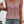 Vrouw draagt roze mouwloze top met knoopsluiting en kanten details, gecombineerd met denim shorts. Zomerse mode, casual outfit, dameskleding.