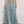 Vrouw in lange denim rok met elastische tailleband en witte veter, gecombineerd met witte sneakers. Trendy casual damesmode.