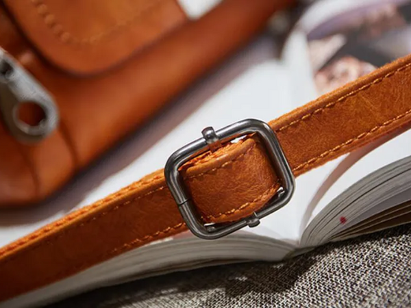 Leren bruine tasriem met metalen gesp op een open boek. Hoogwaardige leren accessoires, stijlvolle mode, close-up detail.