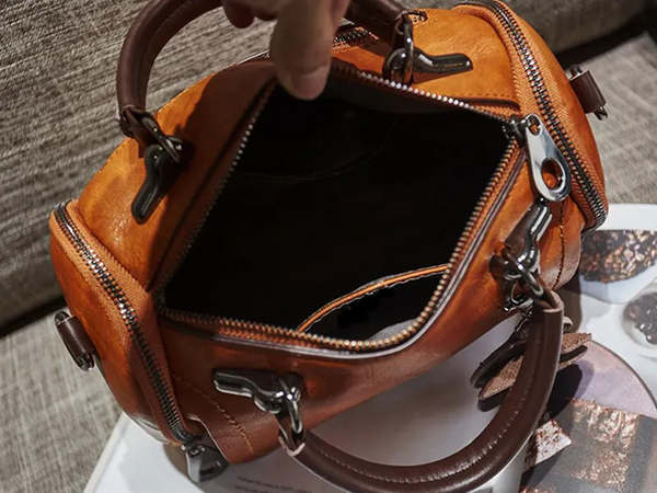 Bruine leren handtas met meerdere ritsen en handvatten, open bovenaanzicht. Luxe damesaccessoire, stijlvolle tas voor dagelijks gebruik.