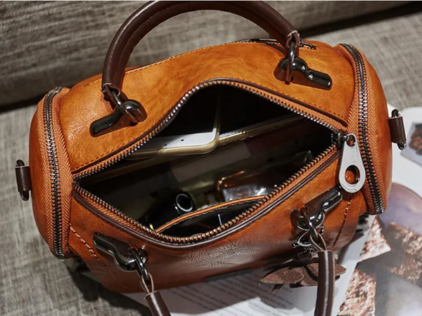 Leren handtas met rits, bruine kleur, open met zichtbare inhoud zoals smartphone en accessoires. Stijlvolle damesmode, trendy en praktisch ontwerp.