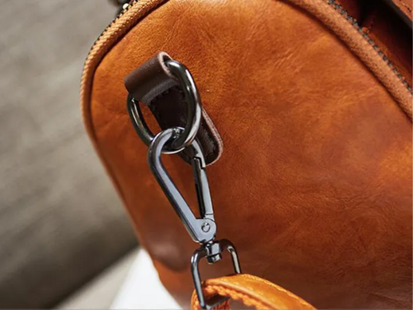 Leren schoudertas met metalen karabijnhaak, detailopname. Hoogwaardige bruine tas, stijlvolle accessoire voor dagelijks gebruik.