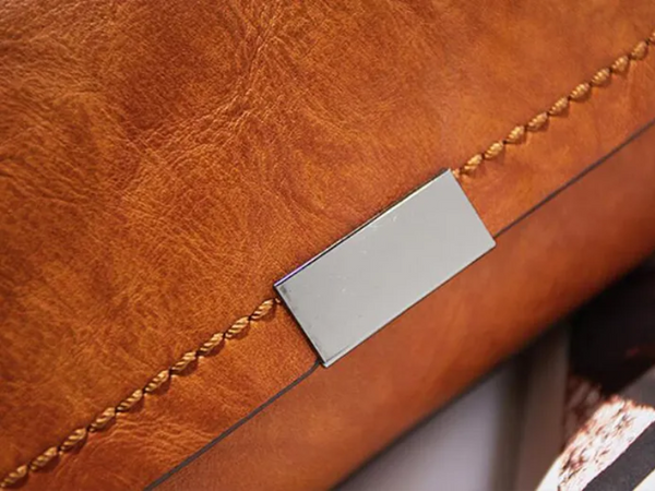 Luxe bruine leren tas met metalen plaatje en decoratieve stiksels, stijlvolle handtas voor dames, modieuze accessoire, hoogwaardige afwerking.