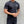 Man in zwarte sportkleding met gewichtenlogo, draagt een mondkapje. Fitness, sportkleding, gezondheid, krachttraining, tatoeages.