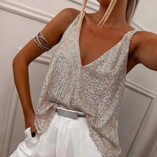 Vrouw in glinsterende, zilveren pailletten top met V-hals en witte broek, stijlvolle armband, modieuze outfit, elegante avondkleding.