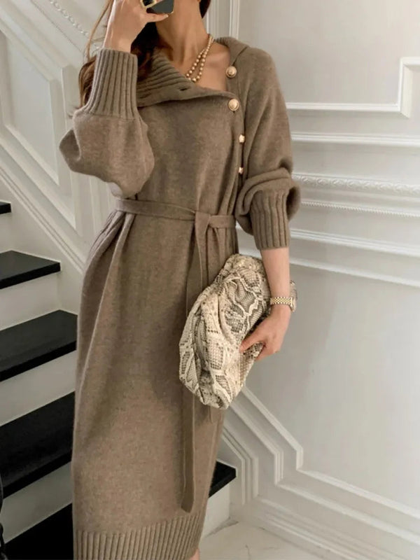 Vrouw in elegante bruine gebreide jurk met knopen en ceintuur, houdt een slangenleren clutch vast. Stijlvolle herfstmode, chique dameskleding.