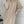 Vrouw in beige gebreide jurk met knopen, poseert op trap. Stijlvolle wintermode, comfortabele oversized pasvorm, trendy dameskleding.