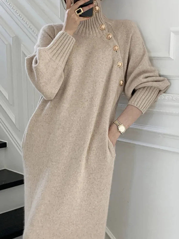 Vrouw in beige gebreide jurk met knopen, poseert op trap. Stijlvolle wintermode, comfortabele oversized pasvorm, trendy dameskleding.