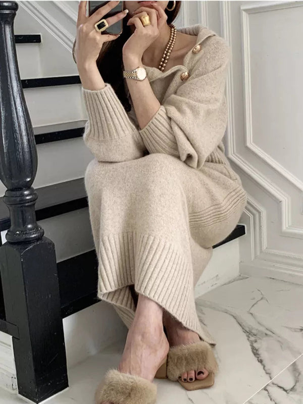 Vrouw in beige gebreide jurk met gouden sieraden en bontslippers, zittend op trap. Luxe mode, herfstkleding, stijlvolle accessoires.