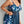 Vrouw in blauwe bloemenprint badpak met tule overlay, sieraden en armband. Plus-size mode, zomerse strandkleding, trendy badmode.