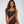 Vrouw in zwart-oranje badpak, strandmode, zomerse zwemkleding, trendy damesbadmode, stijlvolle badkleding, strandoutfit, modieuze zwemkleding.