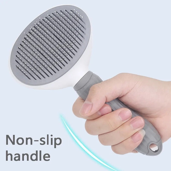 Hand houdt grijze huisdierborstel met antisliphandvat vast, ideaal voor honden- en kattenverzorging. Efficiënte vachtverwijdering en comfortabel gebruik.