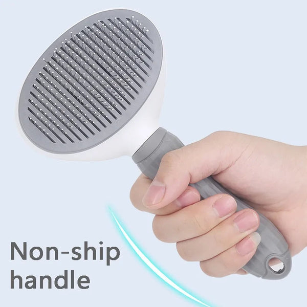 Hand houdt een grijze huisdierborstel met antisliphandvat vast, ideaal voor honden- en kattenverzorging. Efficiënte vachtverzorgingstool.