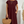 Vrouw in bordeauxrode jurk met korte mouwen, draagt een strooien handtas en gouden sieraden. Stijlvolle zomeroutfit, casual en elegant.