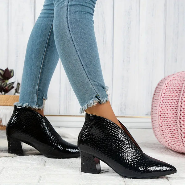 Dames enkellaarsjes met zwarte krokodillenprint, blokhak en puntige neus, gedragen met blauwe skinny jeans. Stijlvolle herfstmode.