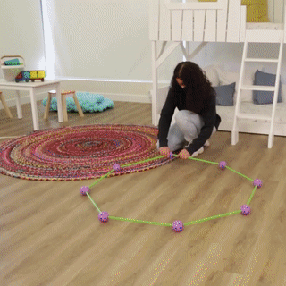 Vrouw bouwt geometrische structuur met kleurrijke stokken en bollen in kinderkamer. Educatief speelgoed, creatief leren, motorische vaardigheden.
