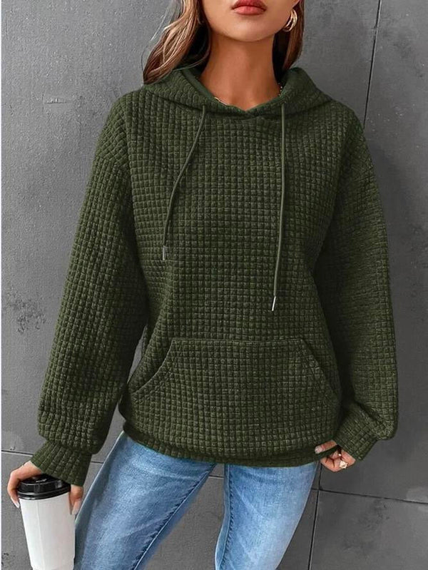 Vrouw in groene geribbelde hoodie met capuchon, draagt blauwe jeans en houdt een zwarte thermosbeker vast. Casual mode, herfstkleding, comfortabele stijl.